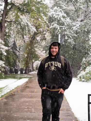 Student walking through falling snow on campus